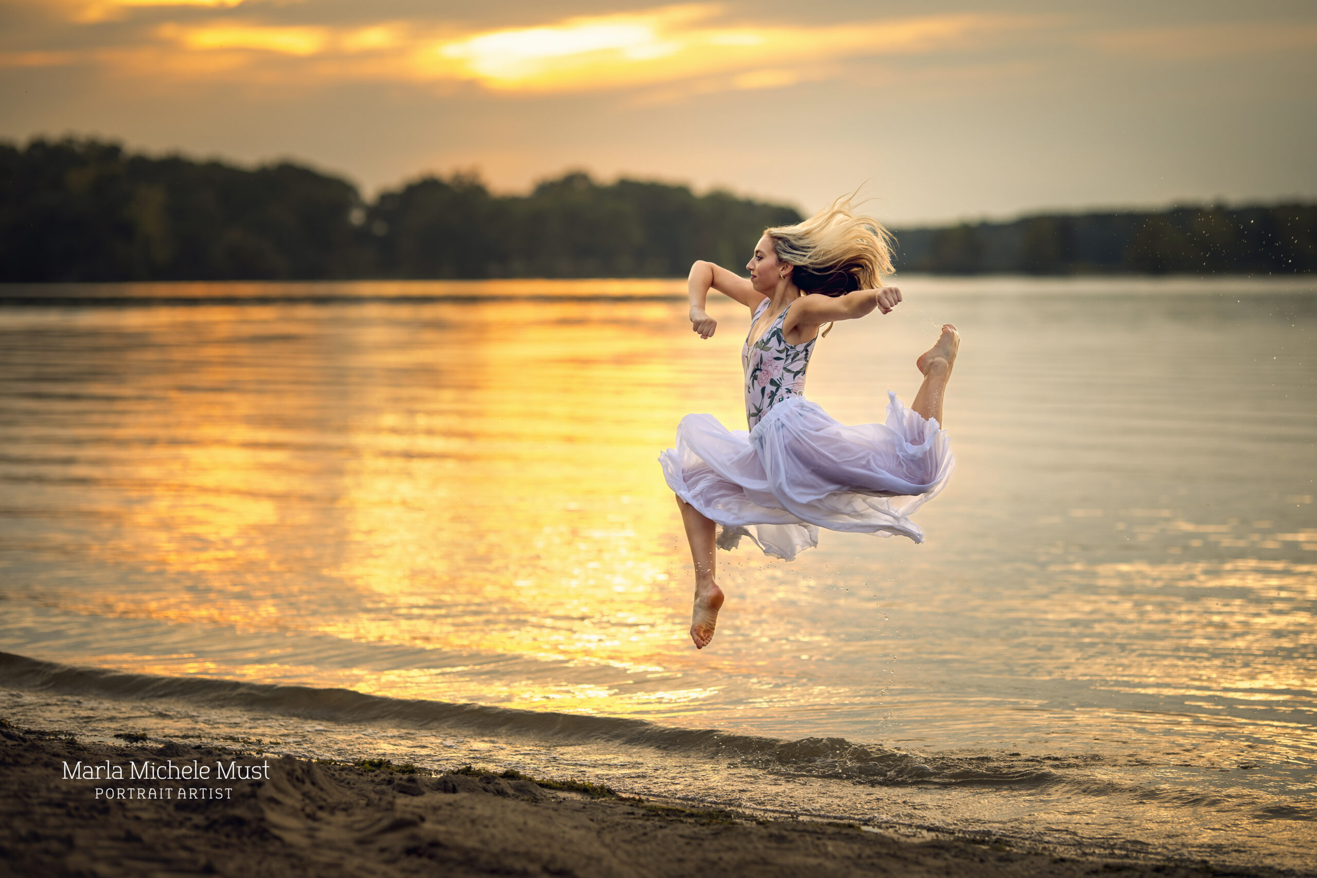 Woman jumps in a lyrical pose on a beach while wearing a flowy dress during a dance photoshoot, taken by a Michigan dance photographer.